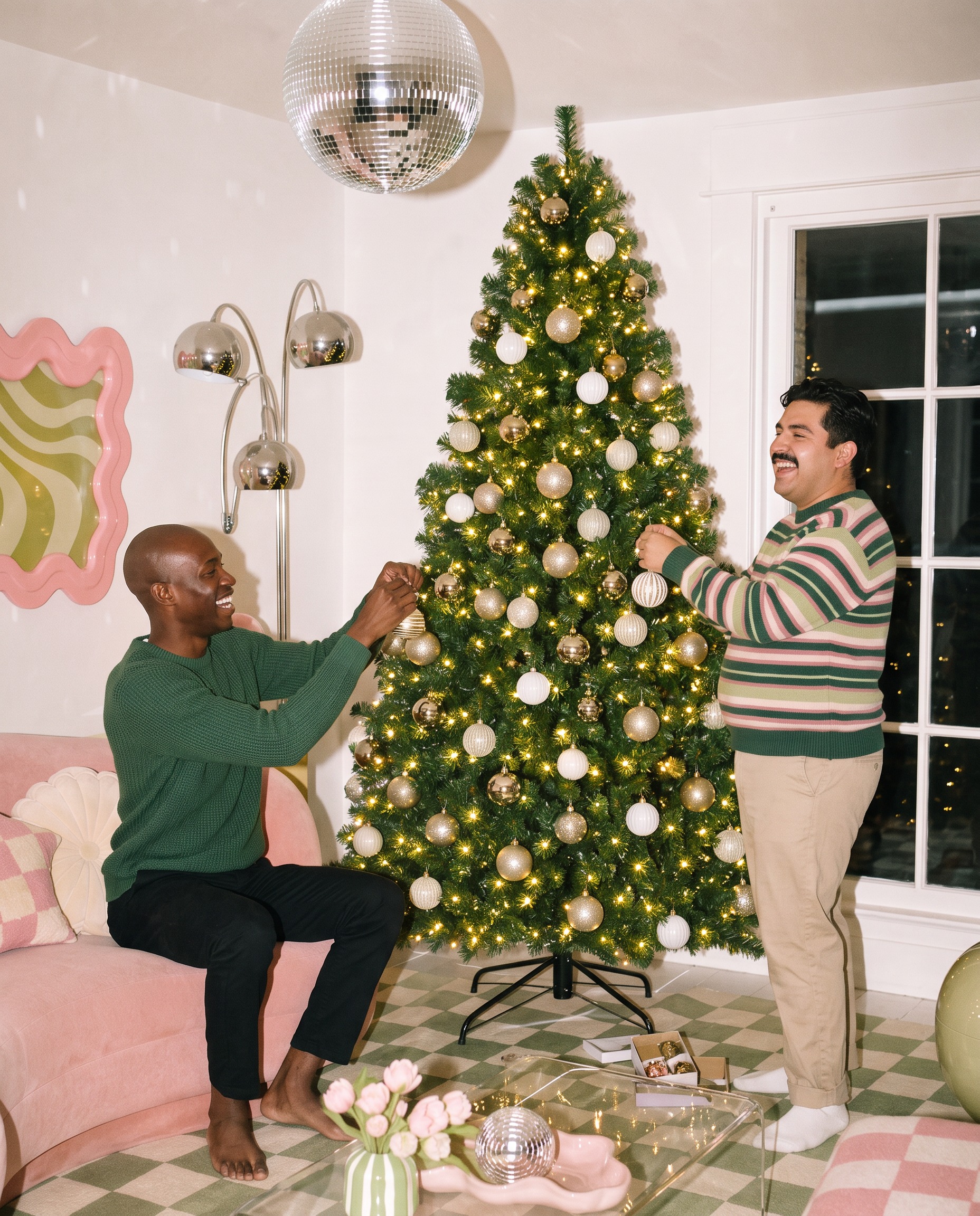 Two friends decorating a tall pre-lit Christmas tree with gold and white baubles